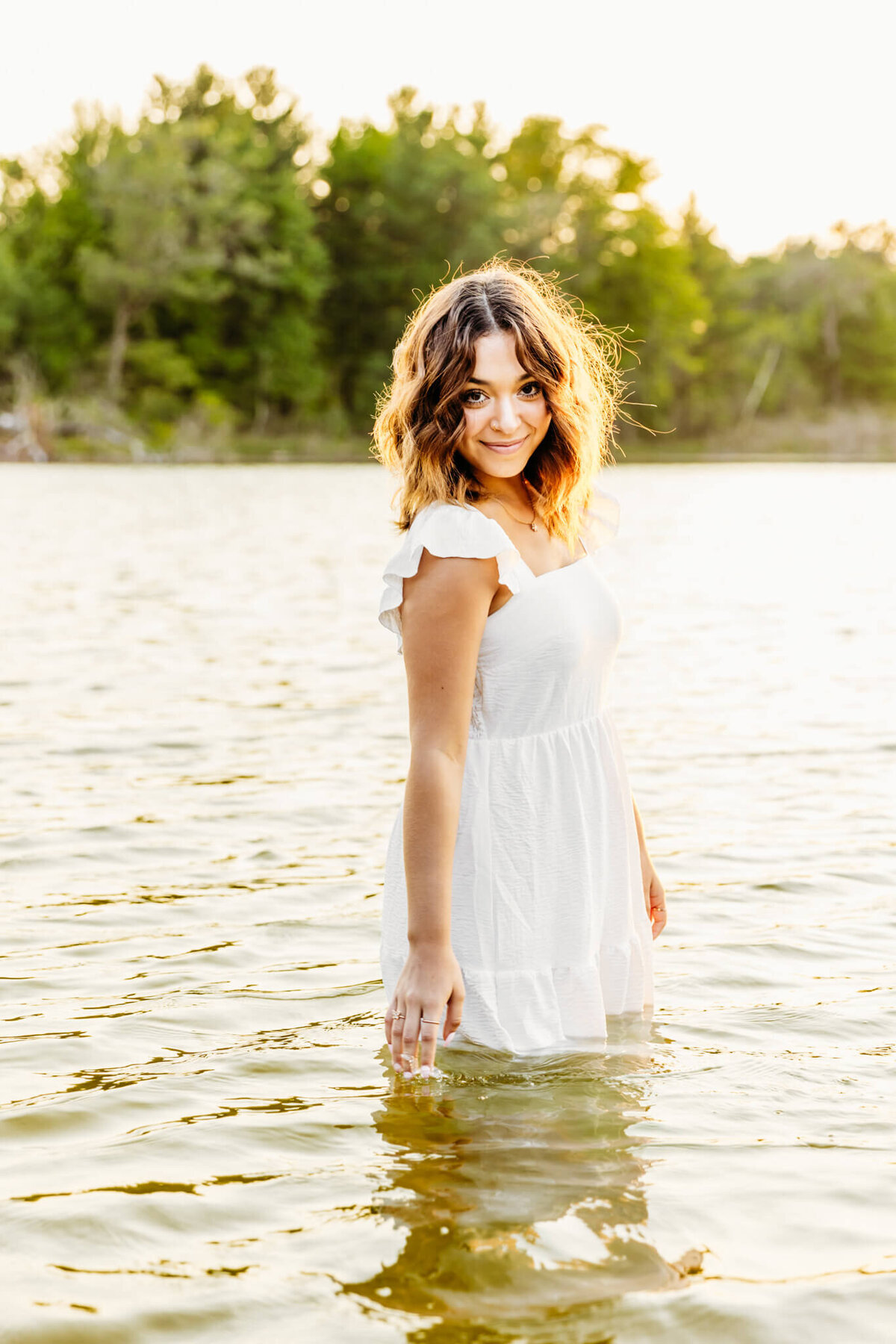 gorgeous high school girl in a white dress walking in a lake at sunset near Oshkosh