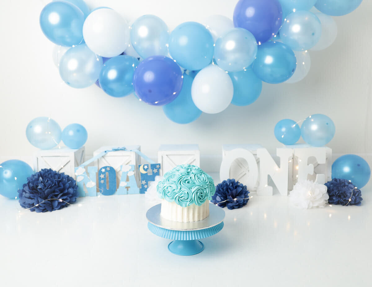 Creative arrangement of balloons and a beautifully designed cake for a custom cake smash photography session in Rochester, NY.