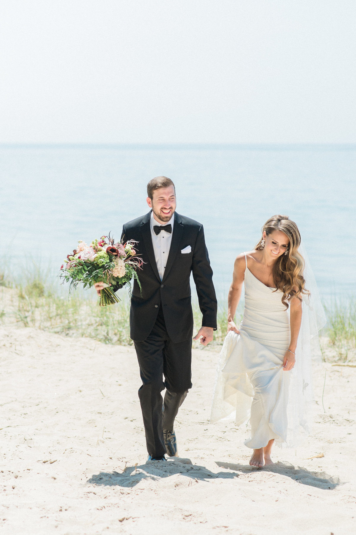 bride and groom smiling walking on beach