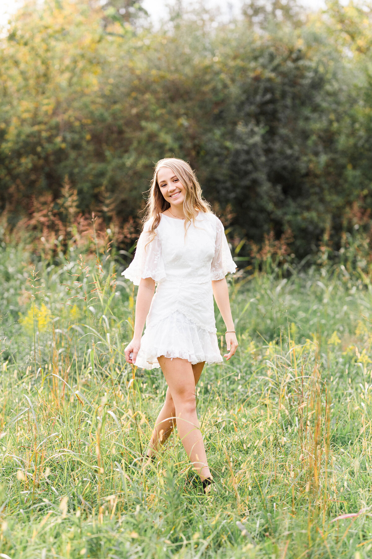 high school senior girl wearing a white dress in a field