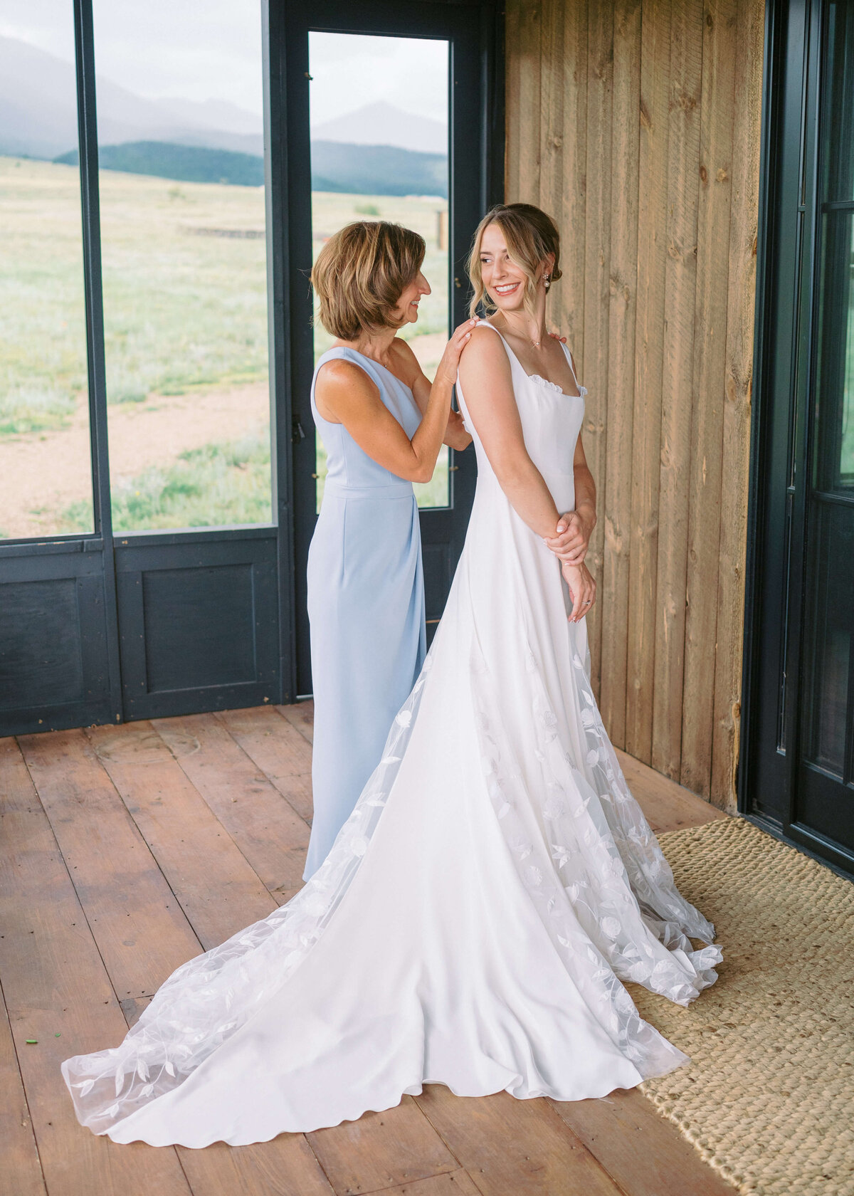 In a light blue dress, the mother of the bride shares a moment with her daughter while standing on the balcony of their cabin in an image taken by Virginia wedding photographer