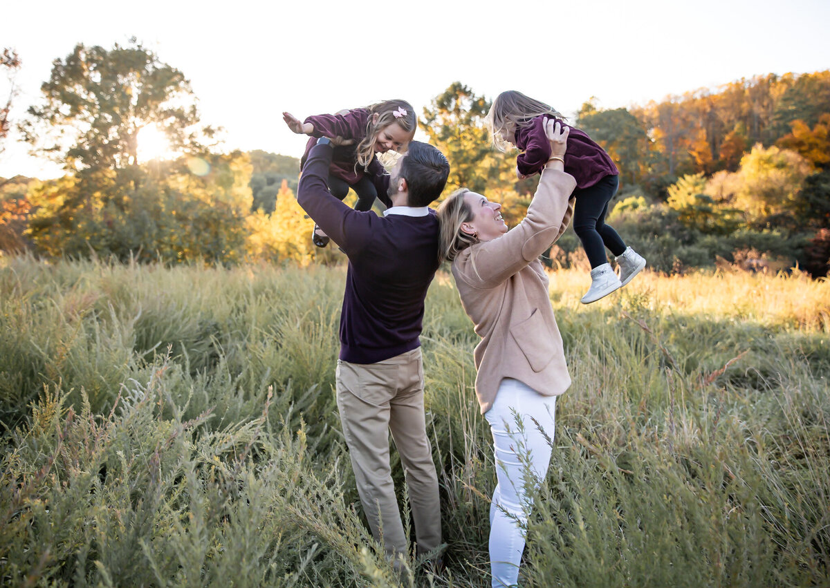 Mommmy and Daddy lifting each child into the air during fall lifestyle family photos