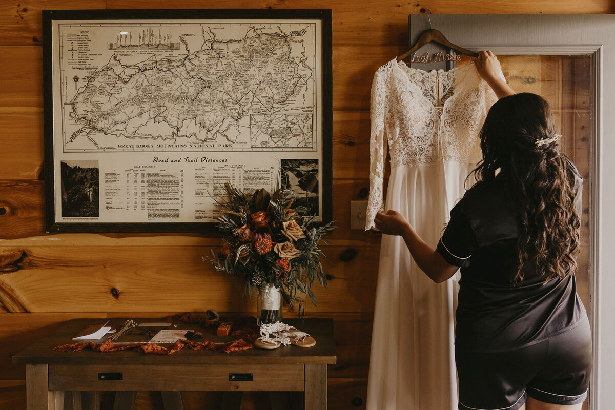 Bride putting her dress on in a cabin