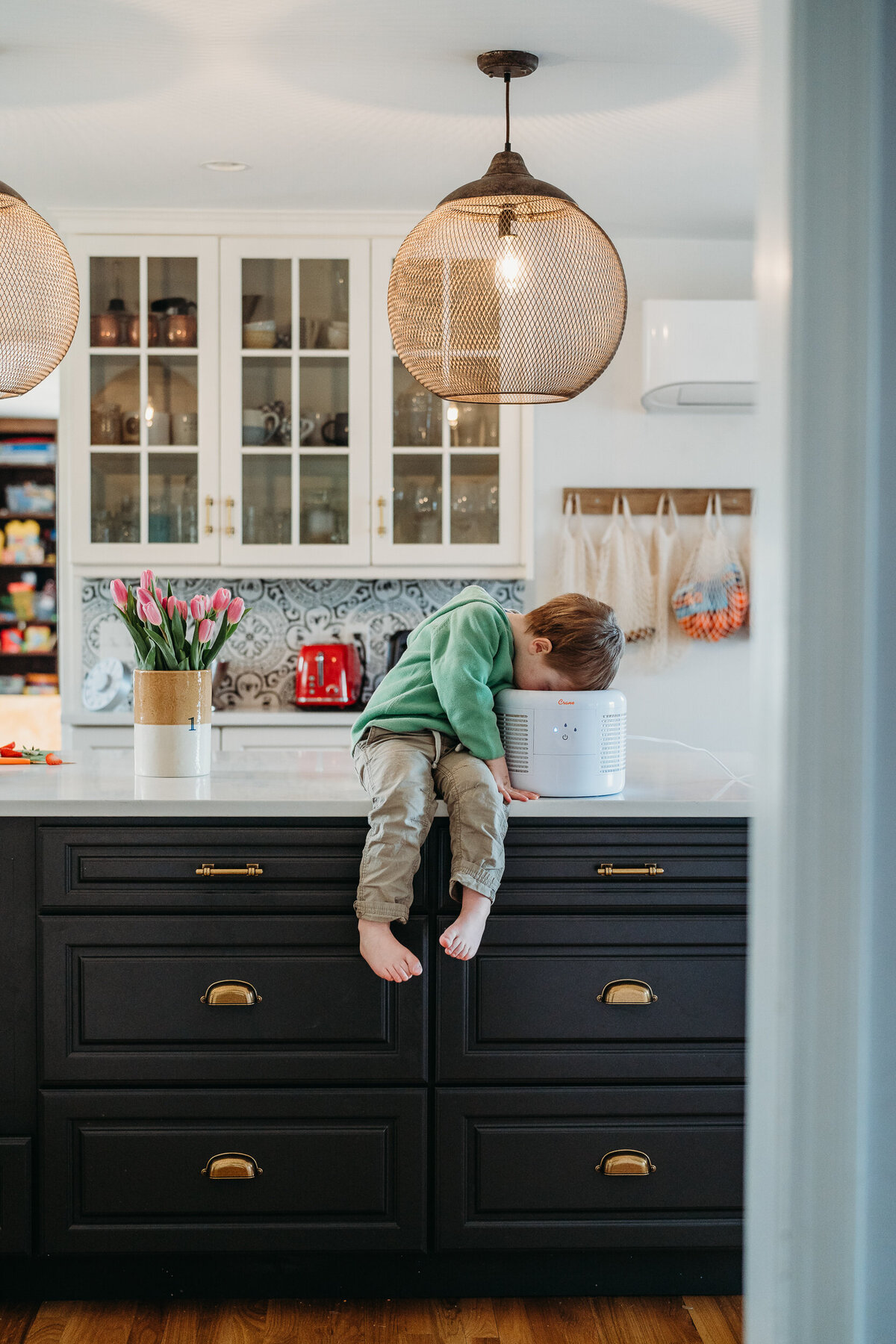 boy stares into air purifier while sitting on counter