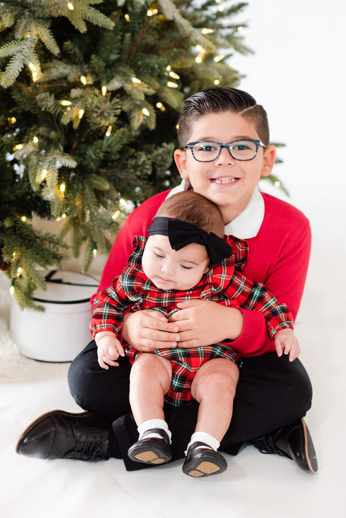 siblings in front of the Christmas tree by Miami Christmas Mini Session Photographers