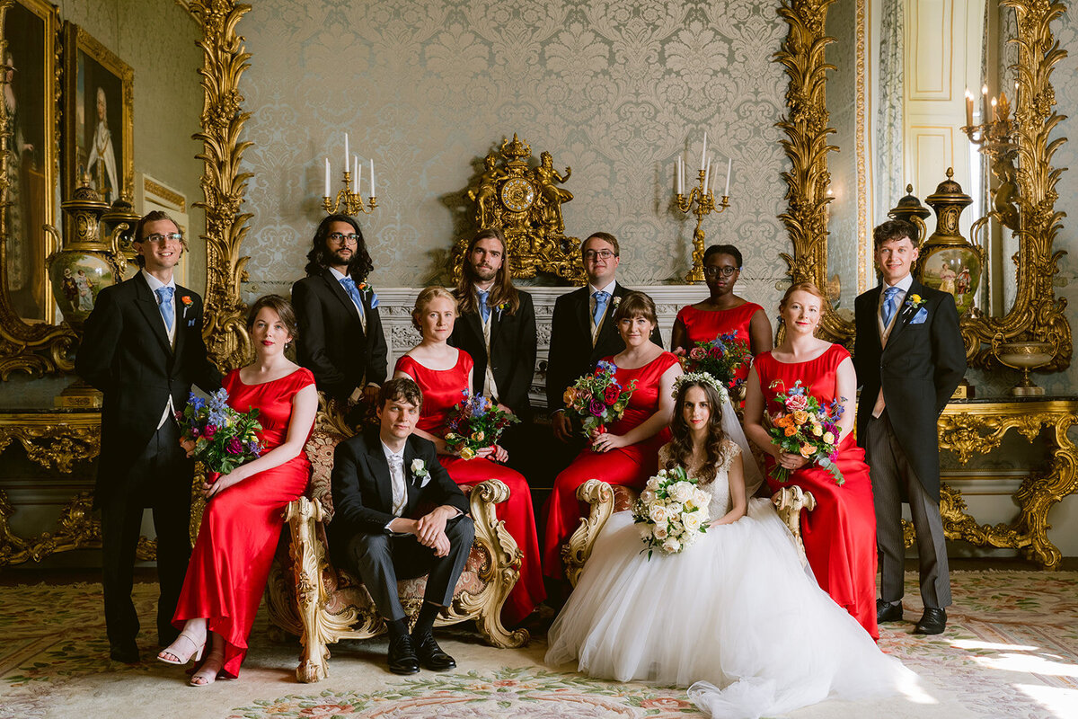 vogue style group photo of the wedding party at allerton castle. bridal party are wearing red and groomsmen wear tails