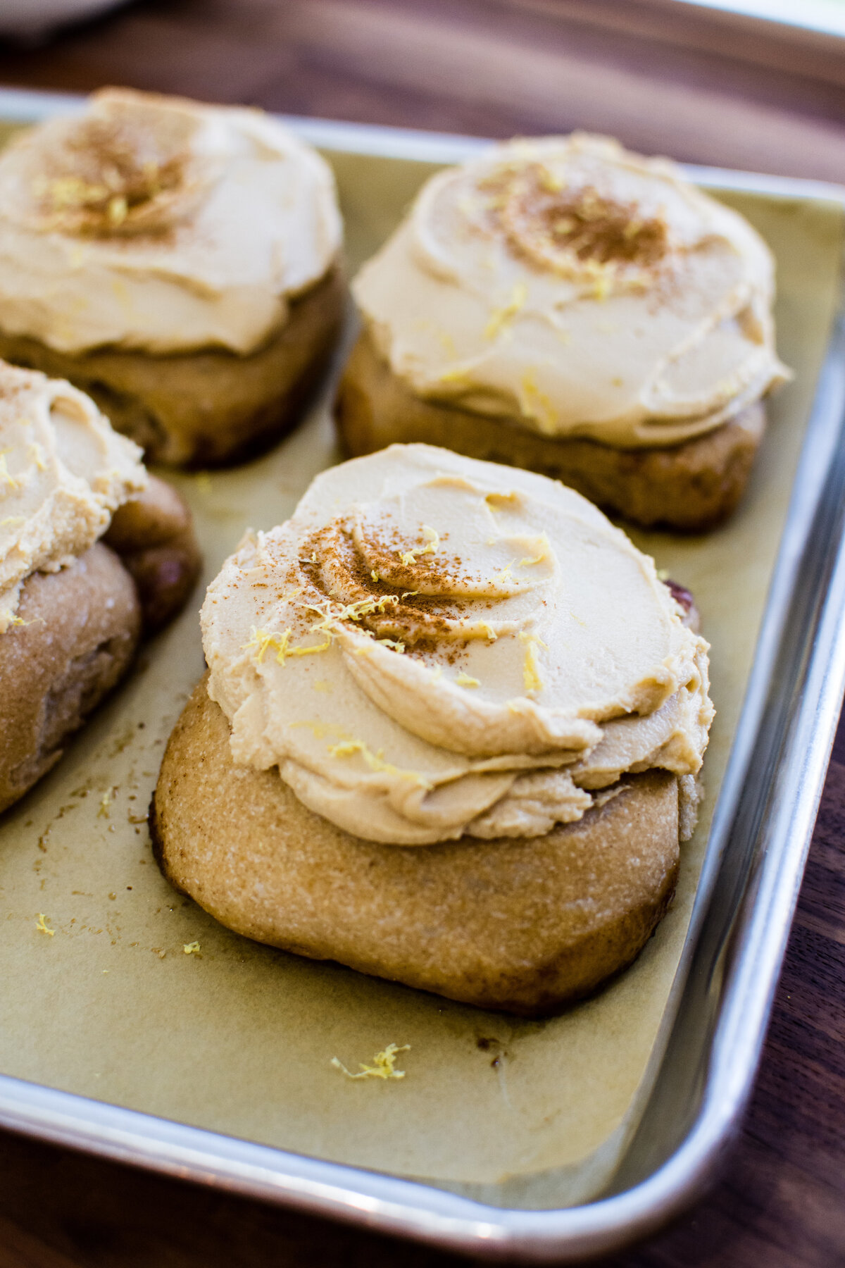 Closeup shot of lemon brown butter espresso cinnamon buns on a silver baking tray