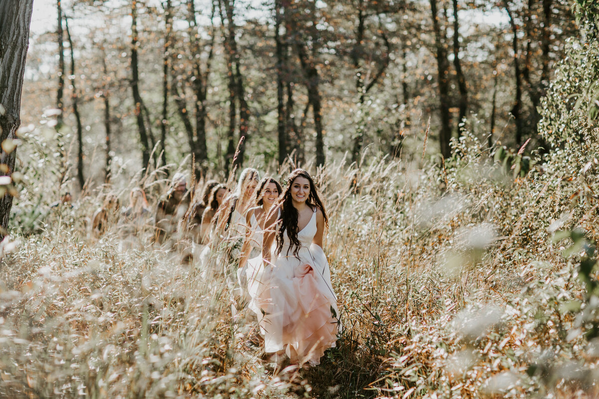 Bride and wedding party walk through New England field