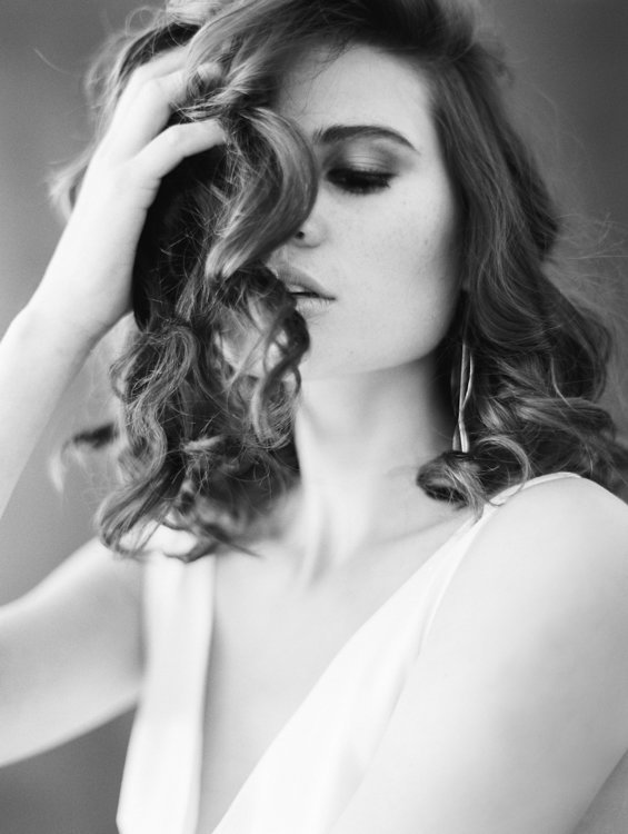 black and white image of model with brown hair curled and slighlty in her face