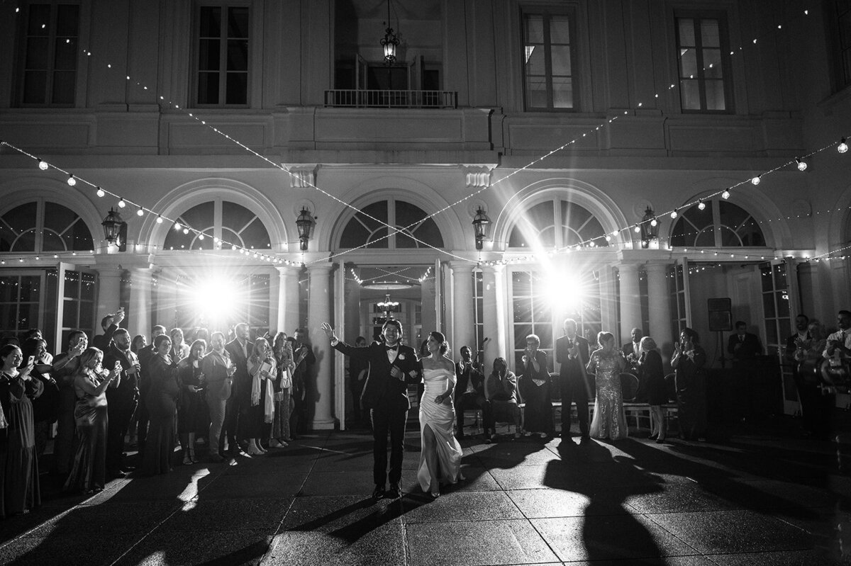 bride and groom make their grand entrance to their reception as guests look on and cheer photo taken by cait fletcher photography a wedding photographer in ct