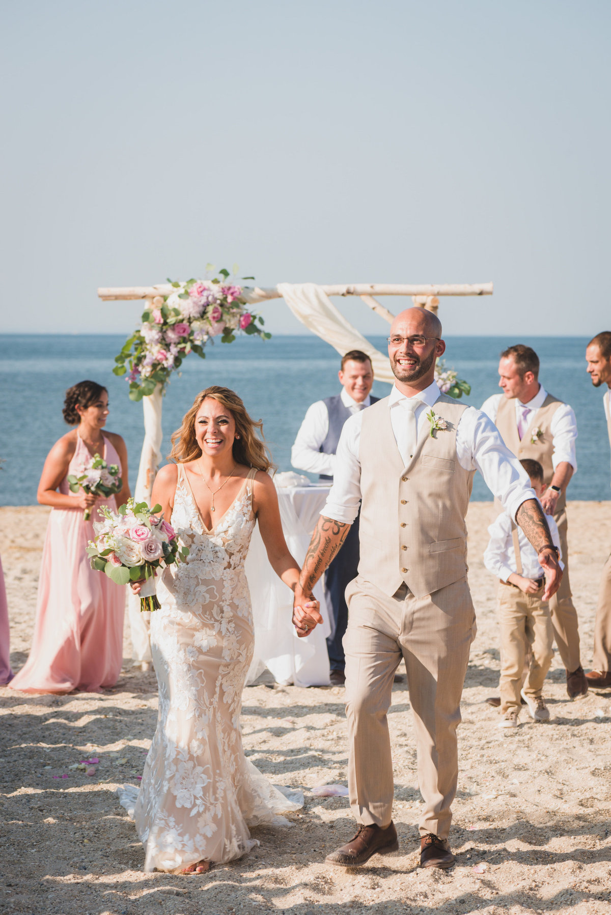 bride and groom walking and holding hands after beach wedding ceremony at Pavilion at Sunken Meadow