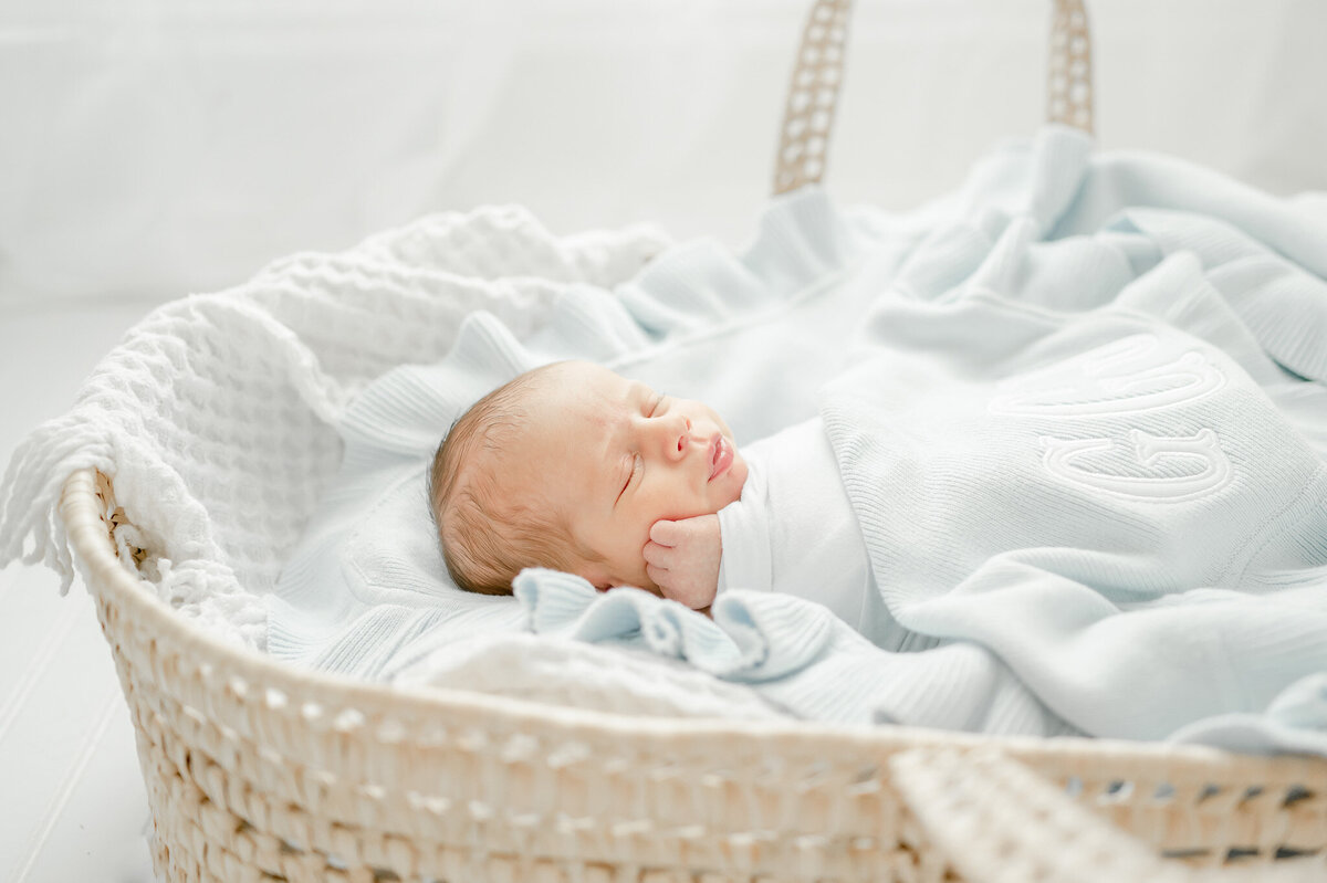 A baby in a blue blanket and basket sleeps In Kristie Lloyd’s Nashville newborn photographer studio