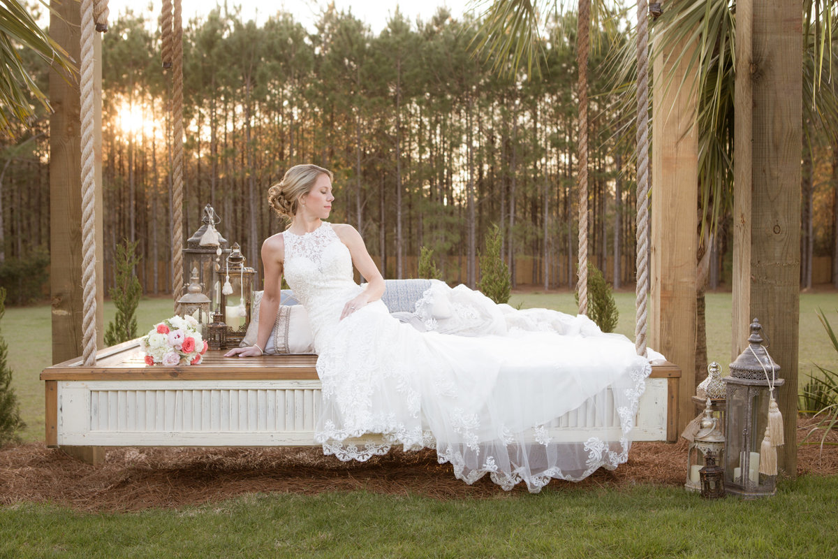 A bride rests on a hanging bed at Bela Sera Gardens in Loxley, Alabama.
