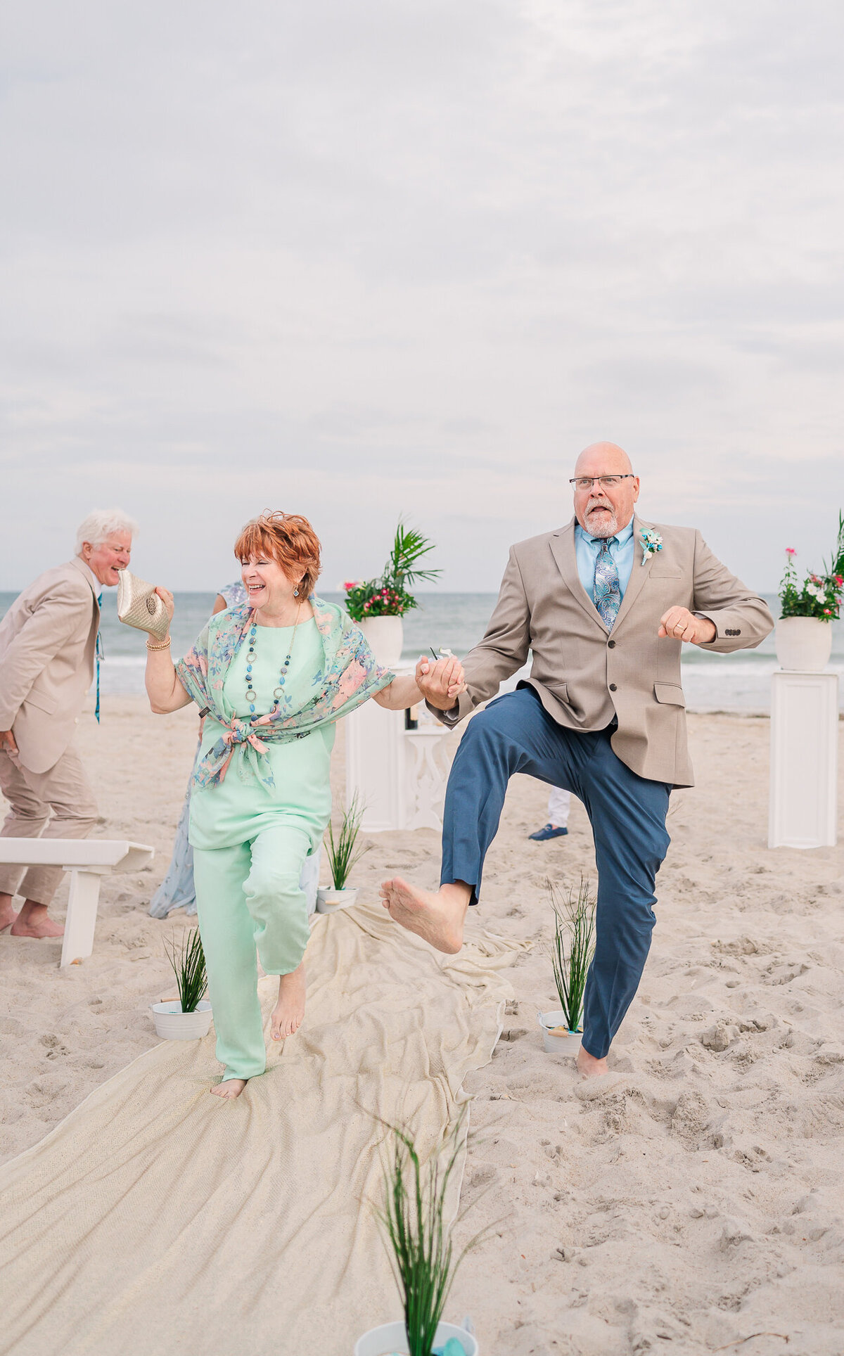 The mom and dad of the bride dancing down the aisle as they leave a wedding ceremony as they are enjoying their Raleigh wedding photos