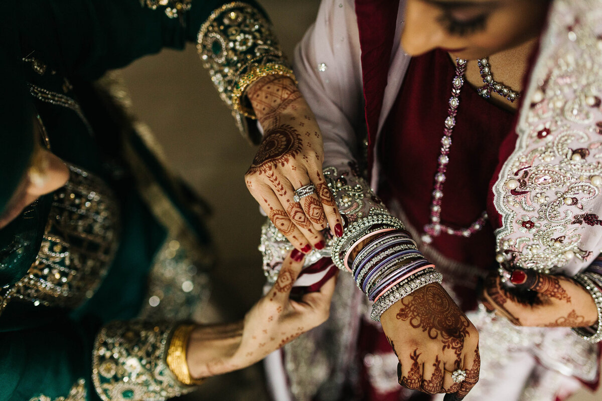 Pakistani bride having her bangles adjusted by her friend at Broughton Sanctuary