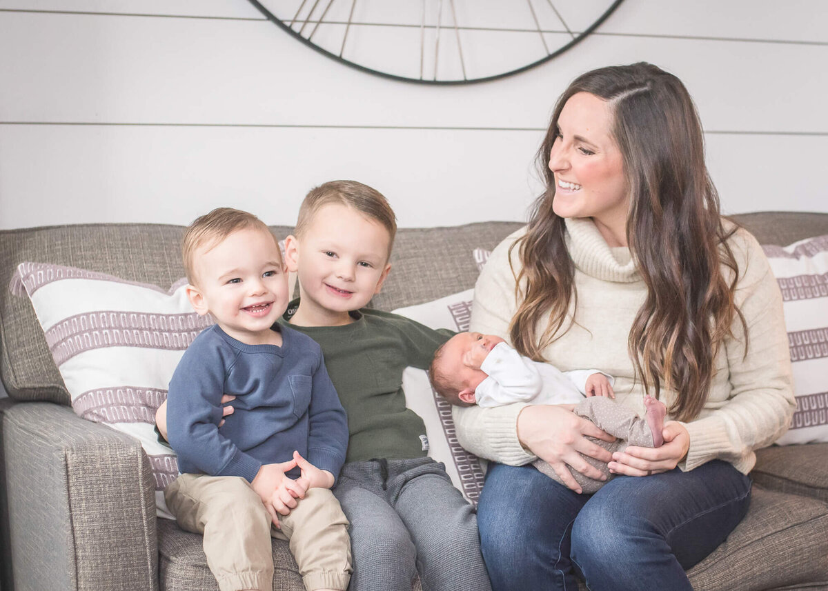 in-home lifestyle newborn session two little boys look at their baby brother being held by mom