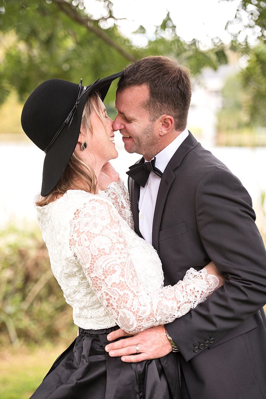 Anniversary vow renewal, close up photo of couple about to share a kiss. She is wearing a black taffeta skirt and she has a long sleeve lace top paired with a black hat.