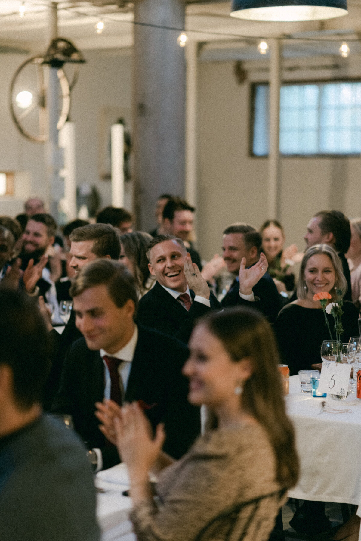 A documentary wedding  photo of guests cheering at speeches in Oitbacka gård captured by wedding photographer Hannika Gabrielsson in Finland