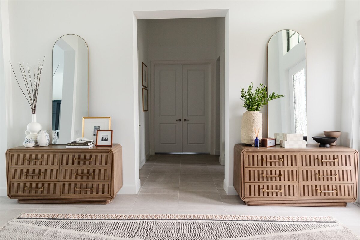 Entryway with wooden dressers and large arch mirrors