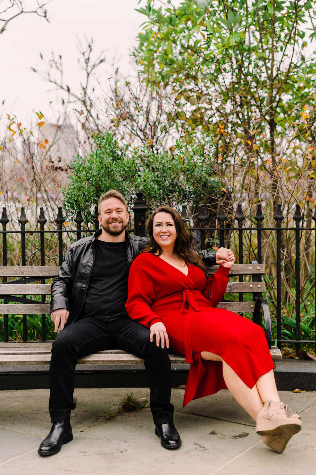 couple sitting on a park bench smiling as the woman leans up against the man