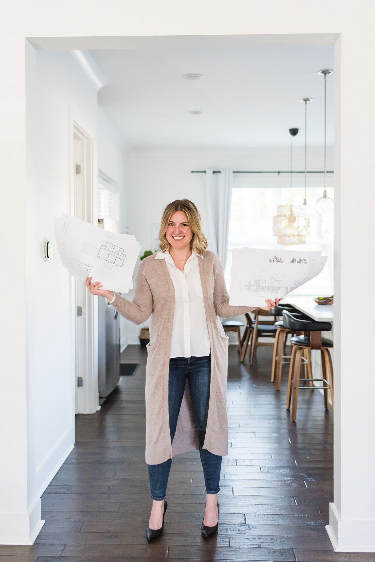 Nashville realtor and architect standing in doorframe with building plans in her hands for a headshot