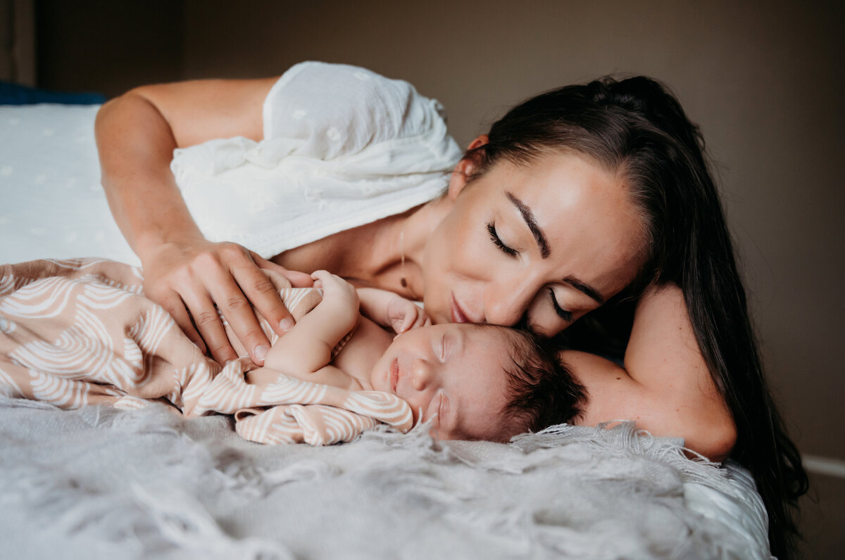 Newborn Photographer, a mother lays beside her new baby on the bed