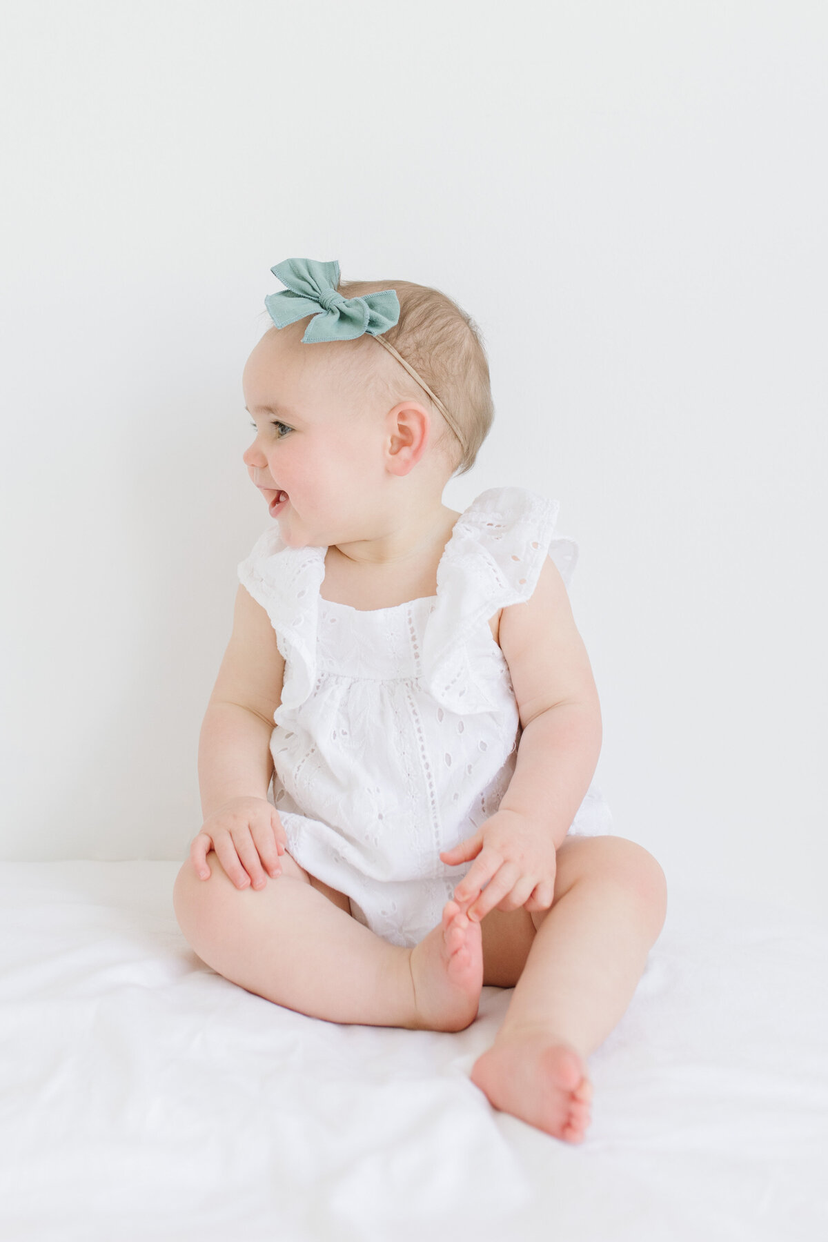 portrait pose of baby girl sitting on bed for photo shoot with Northern Virginia newborn photographer