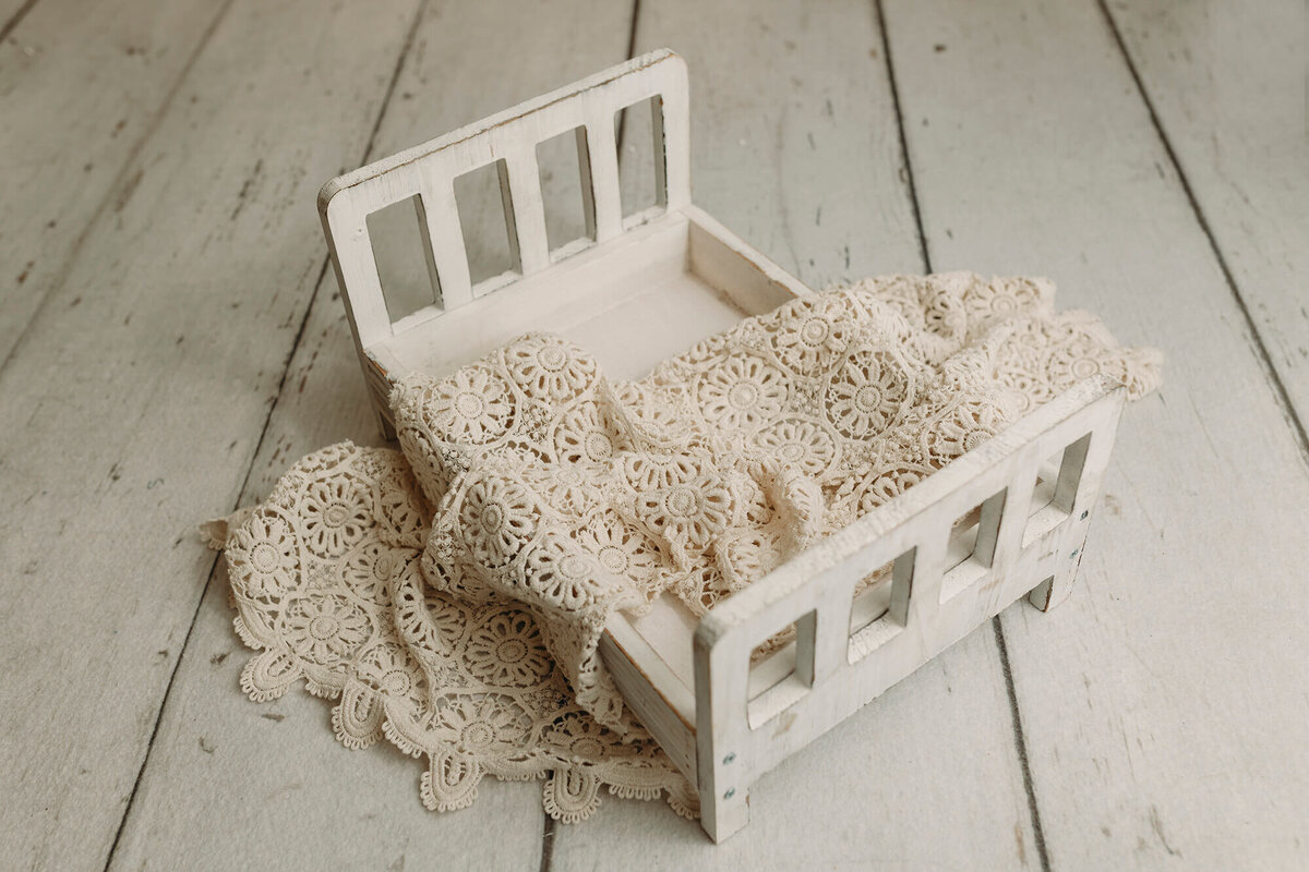 White wooden bed used in newborn sessions.