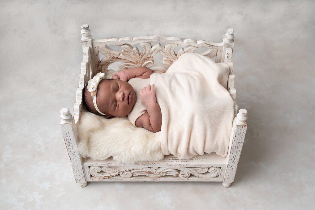 Sleeping newborn in a white themed tiny bed photo shoot by Laura King Photography