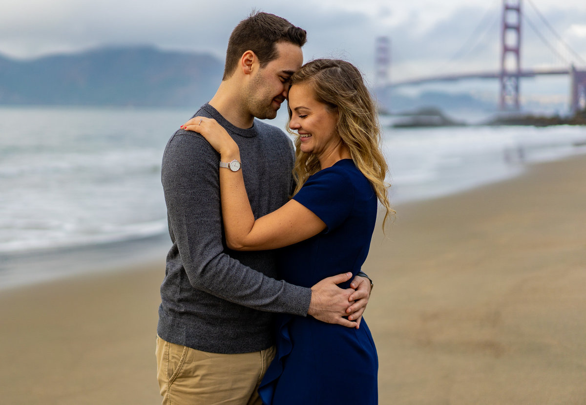 Beach engagement session with couple holding each other