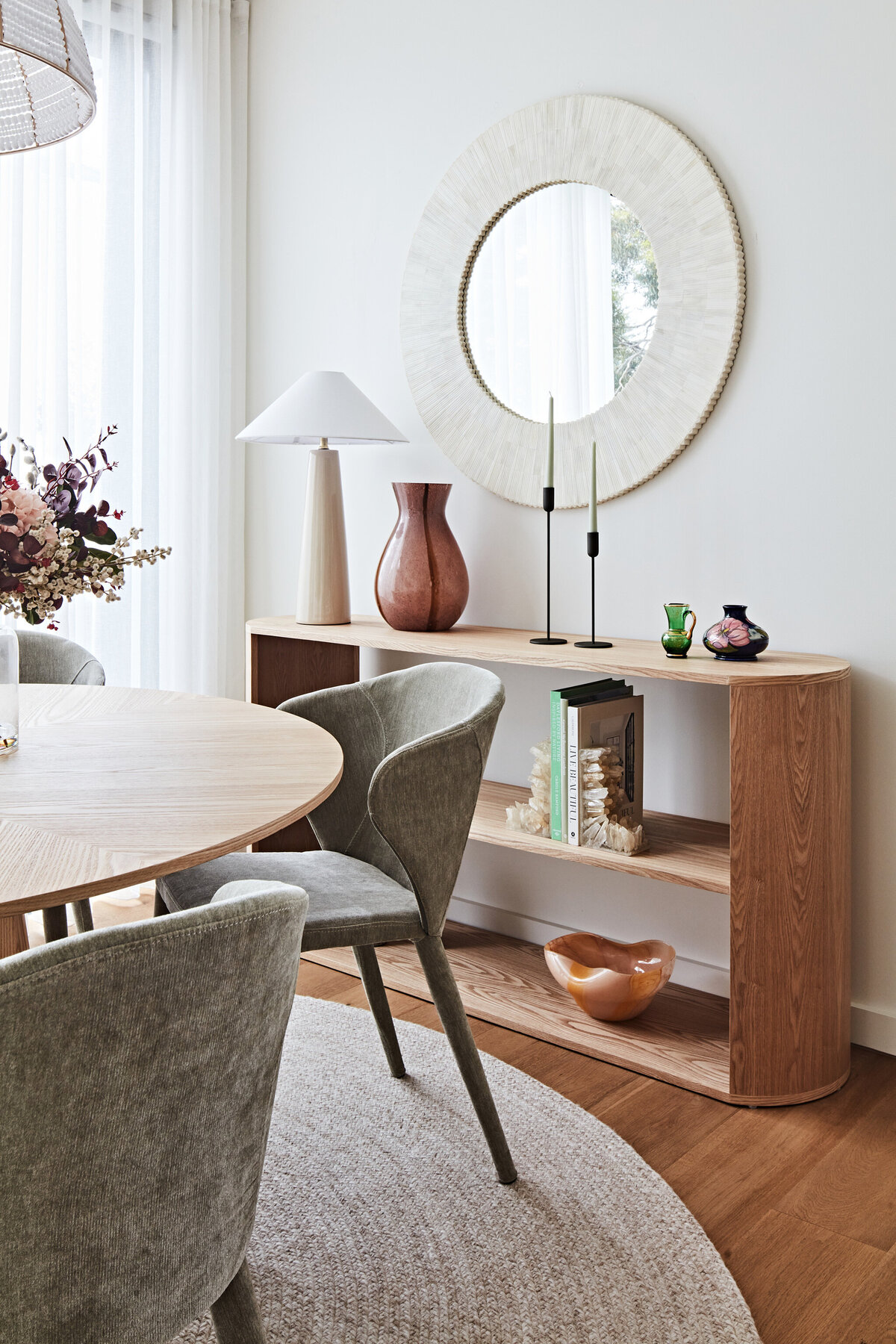 Curated console styling with sculptural décor, round mirror and textured ceramic lamp