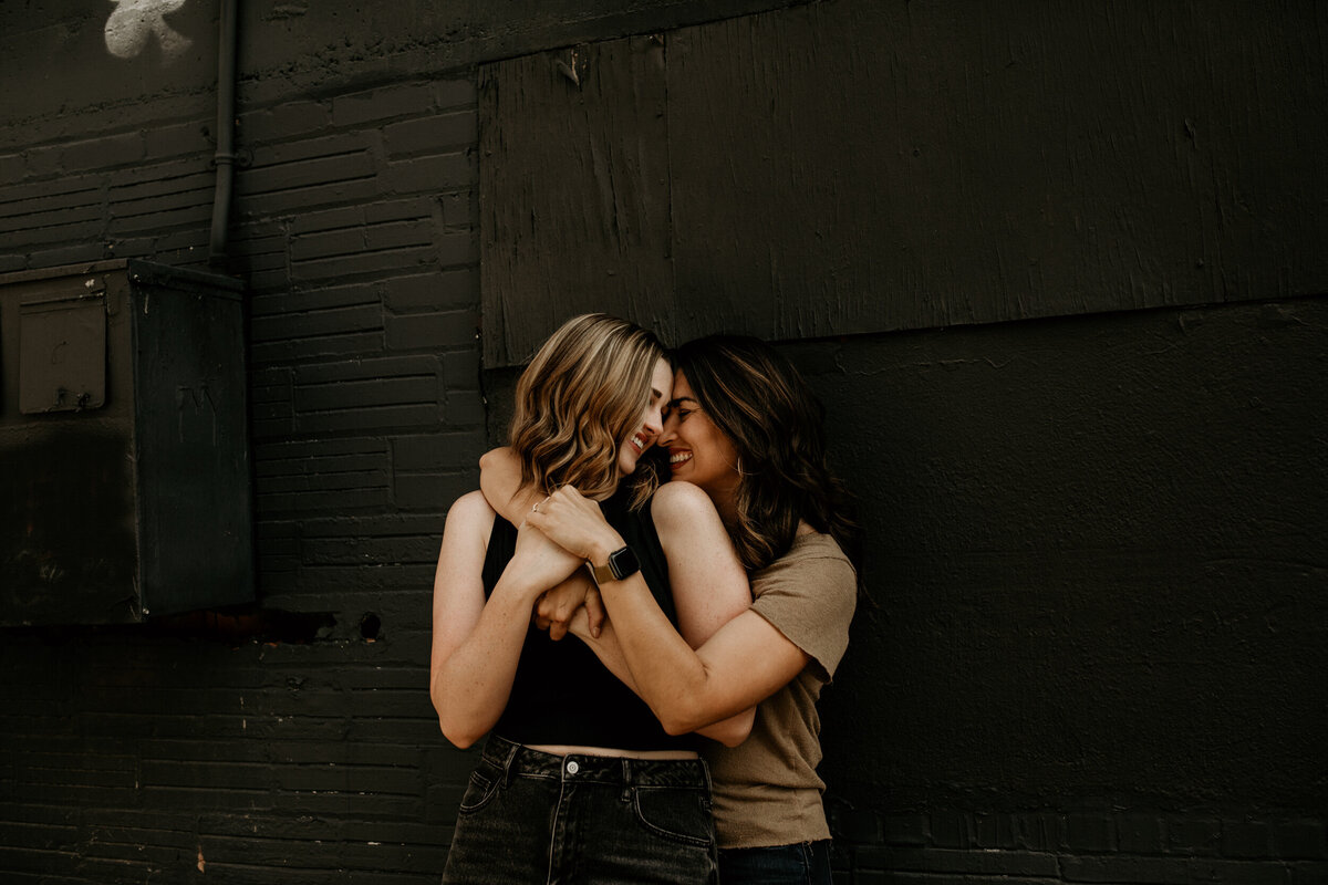 same sex couple hugging each other and laughing in an alley in downtown Albuquerque