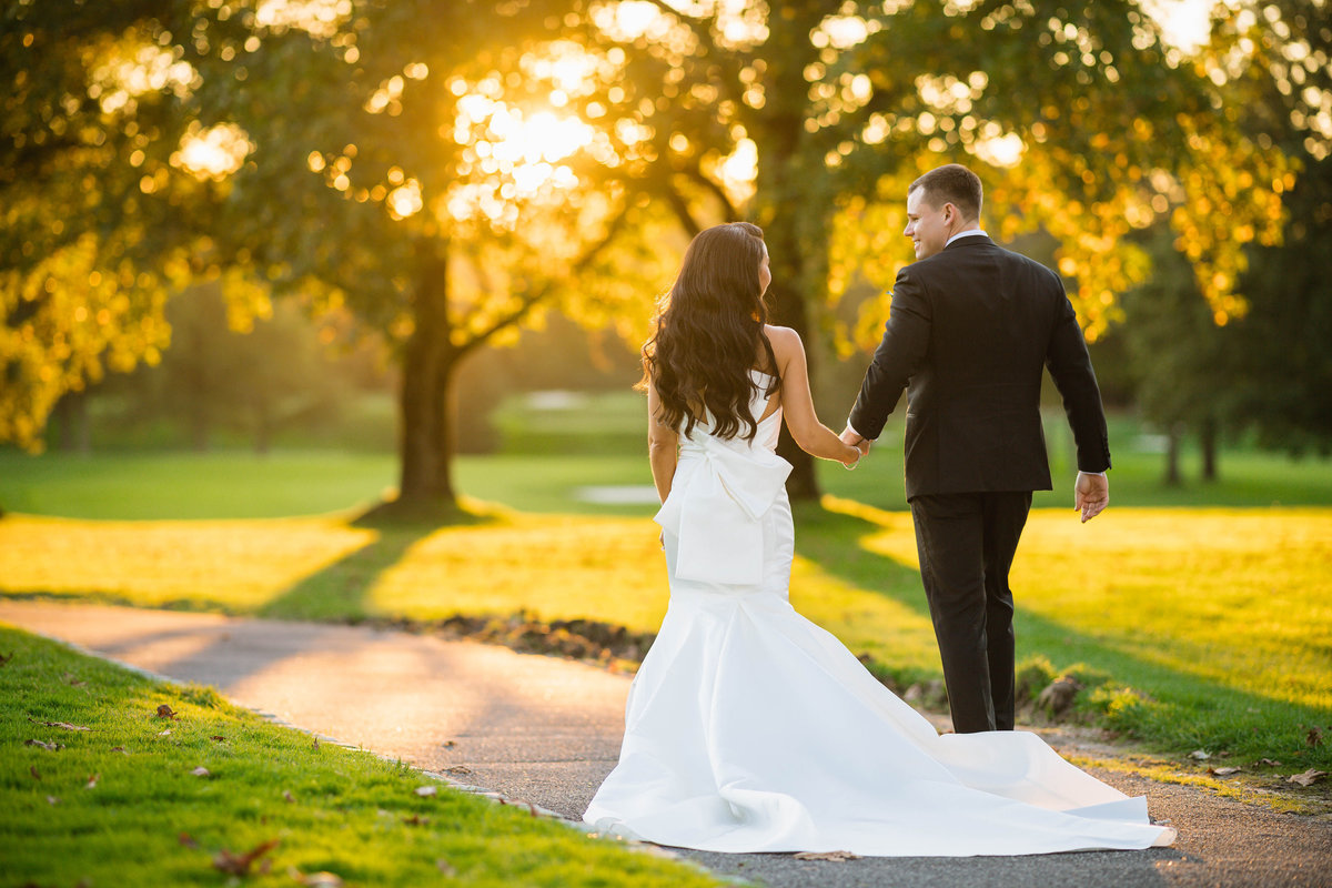 bride and groom walking away on cart path from wedding at The Muttontown Club