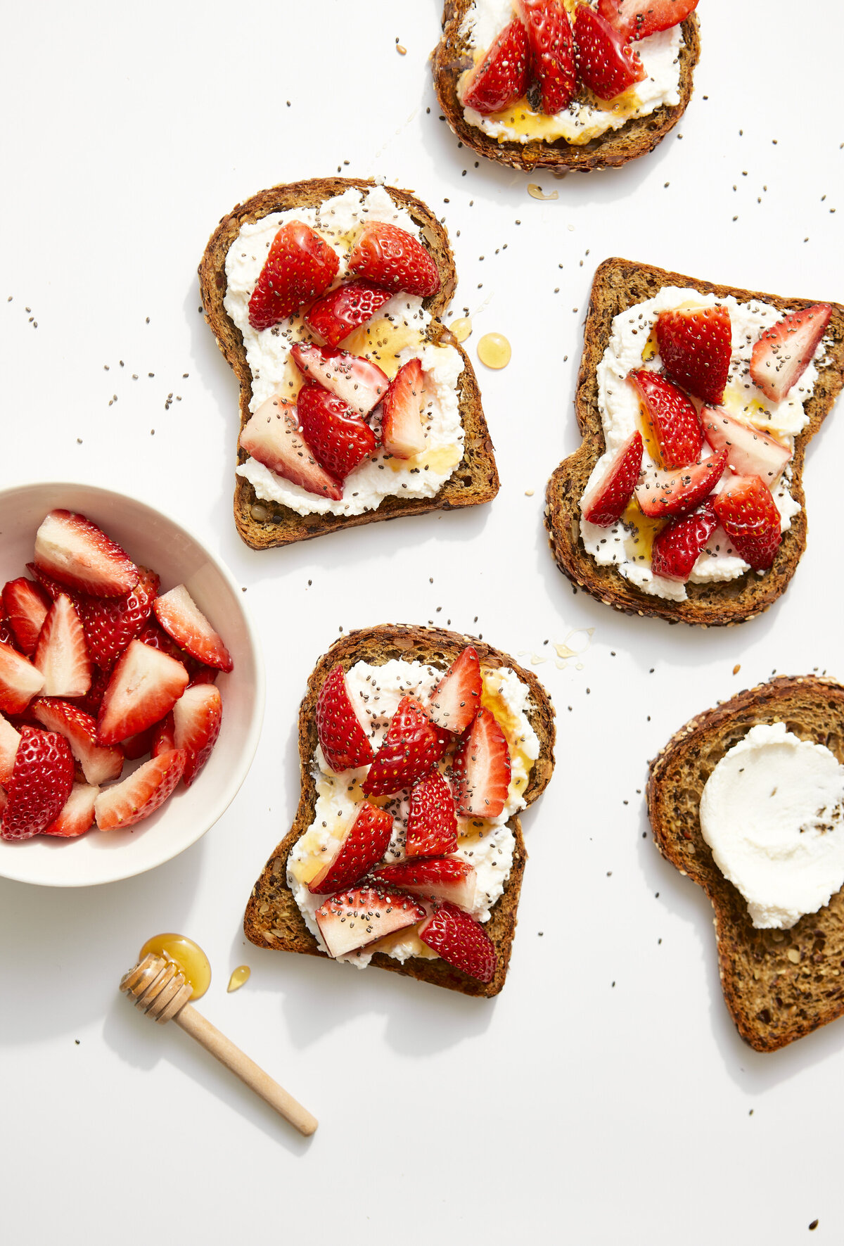 Slices of toast with ricotta cheese and strawberries on it.