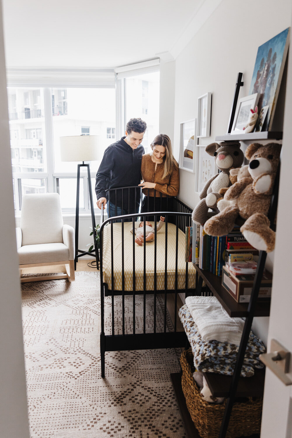 Parents looking at newborn son in his crib during lifestyle newborn session by Claire Binks Photography