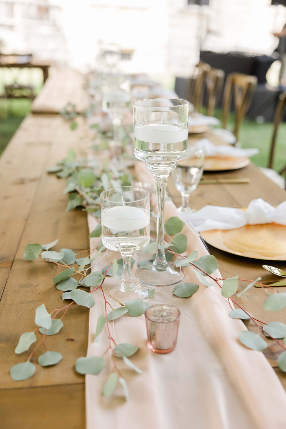 Elegant outdoor dining table setting with a floral centerpiece, water glasses, and gold chairs for park farm winery weddings.