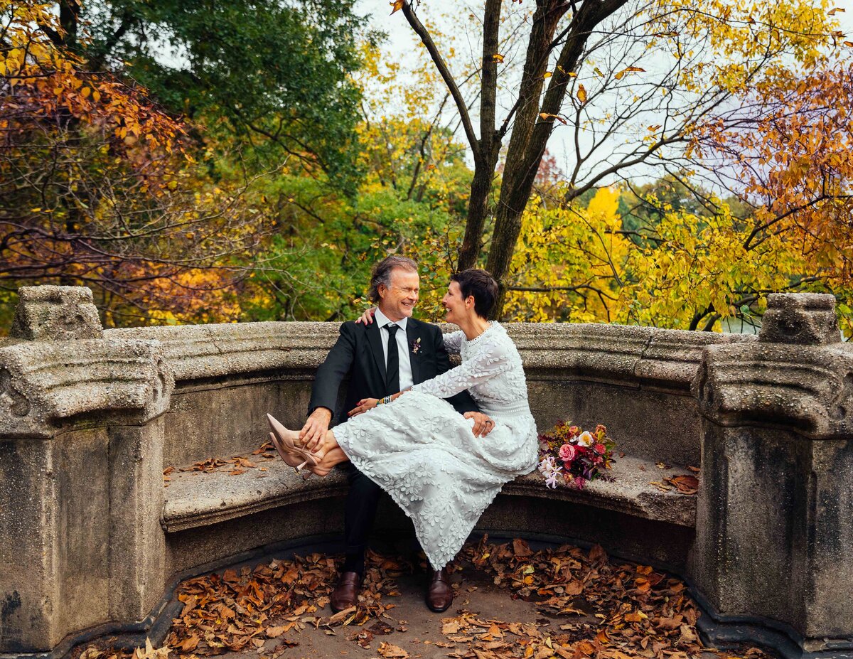 A couple sitting on a stone park bench together.