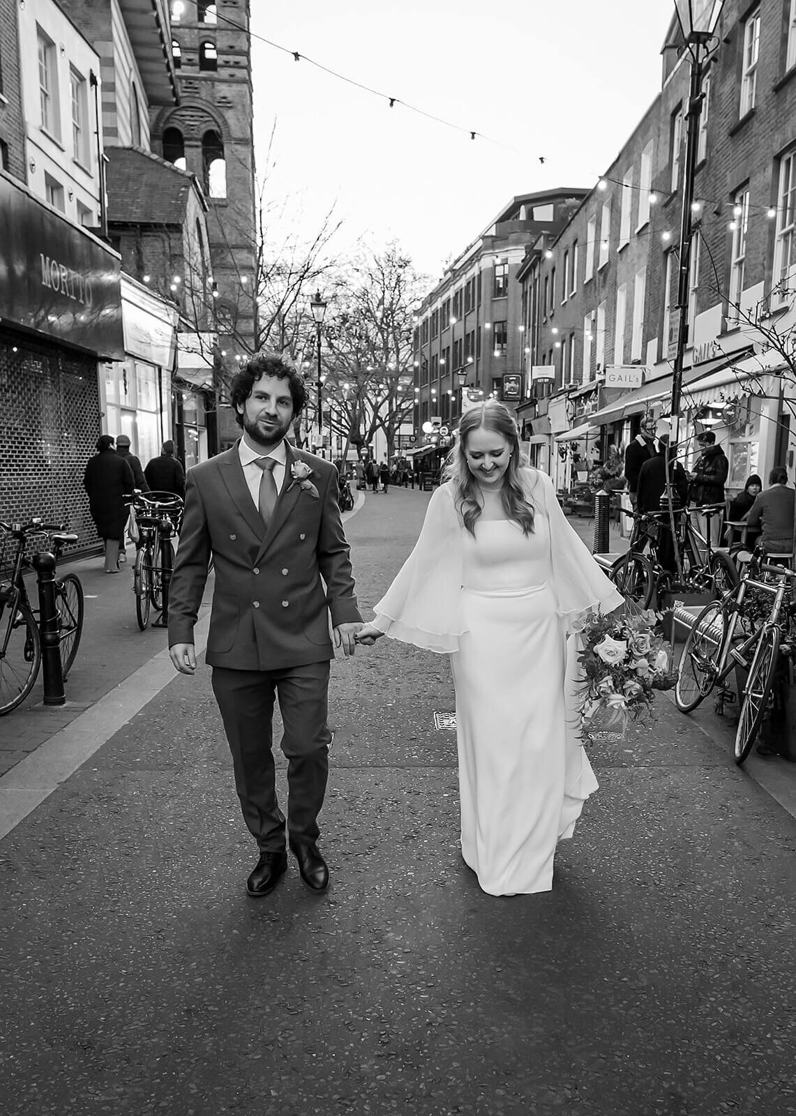 Bride laughing groom smiling, walking down Exmouth Market London