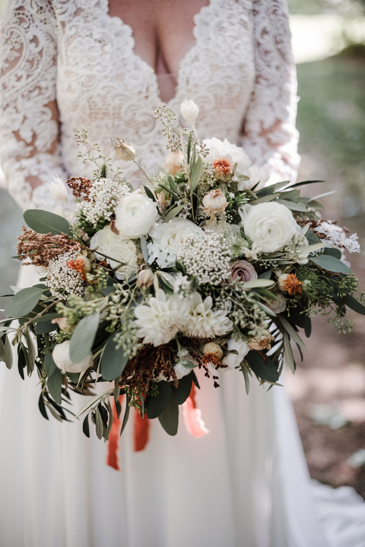 Lacy, textural bridal bouquet with dahlias, ranunculus, olive, rice flower, and dried botanical accents.