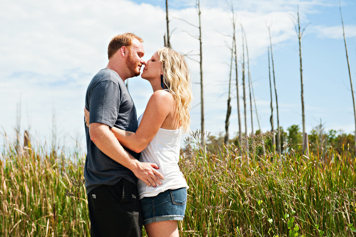 A couple kiss in the north carolina marsh land.