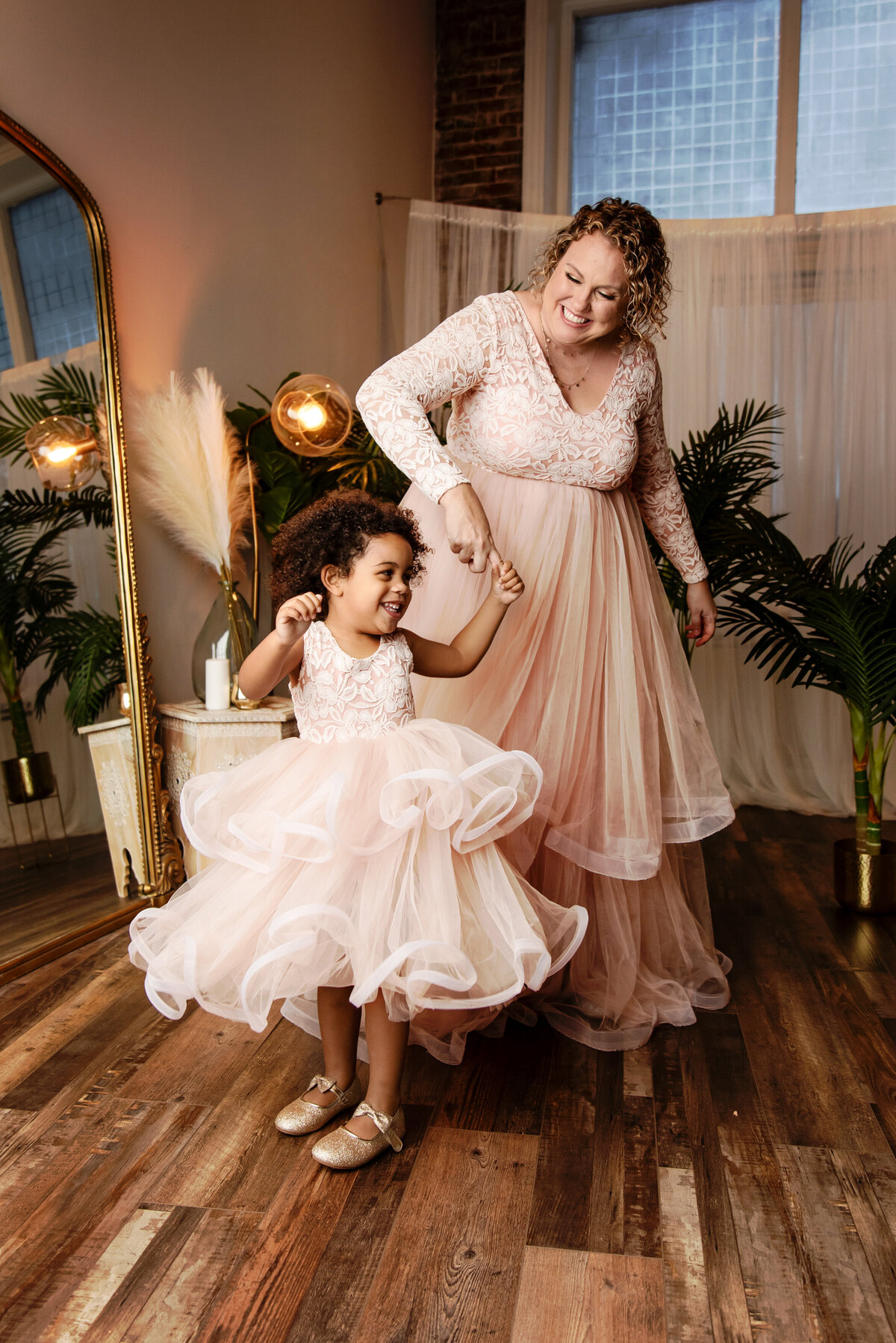 st-louis-family-photographer-mom-and-daughter-in-matching-pink-lace-and-tulle-dresses-dancing-in-front-of-mirrow-and-window