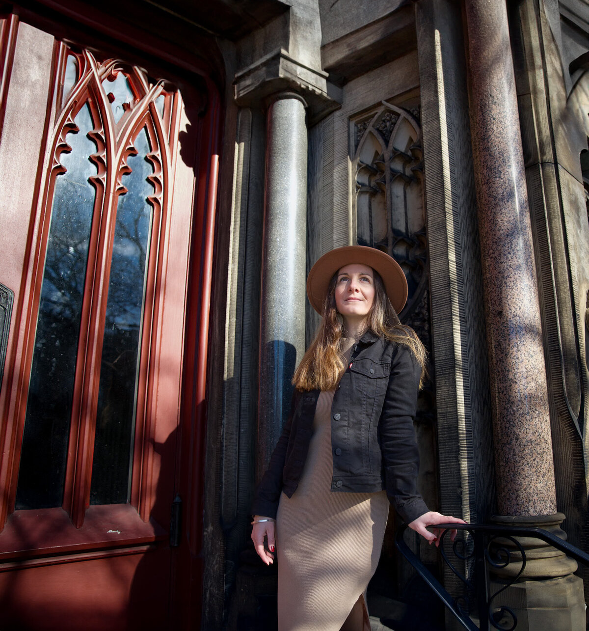 A small business owner smiles during their branding photoshoot in Baltimore, Maryland in front of a church.