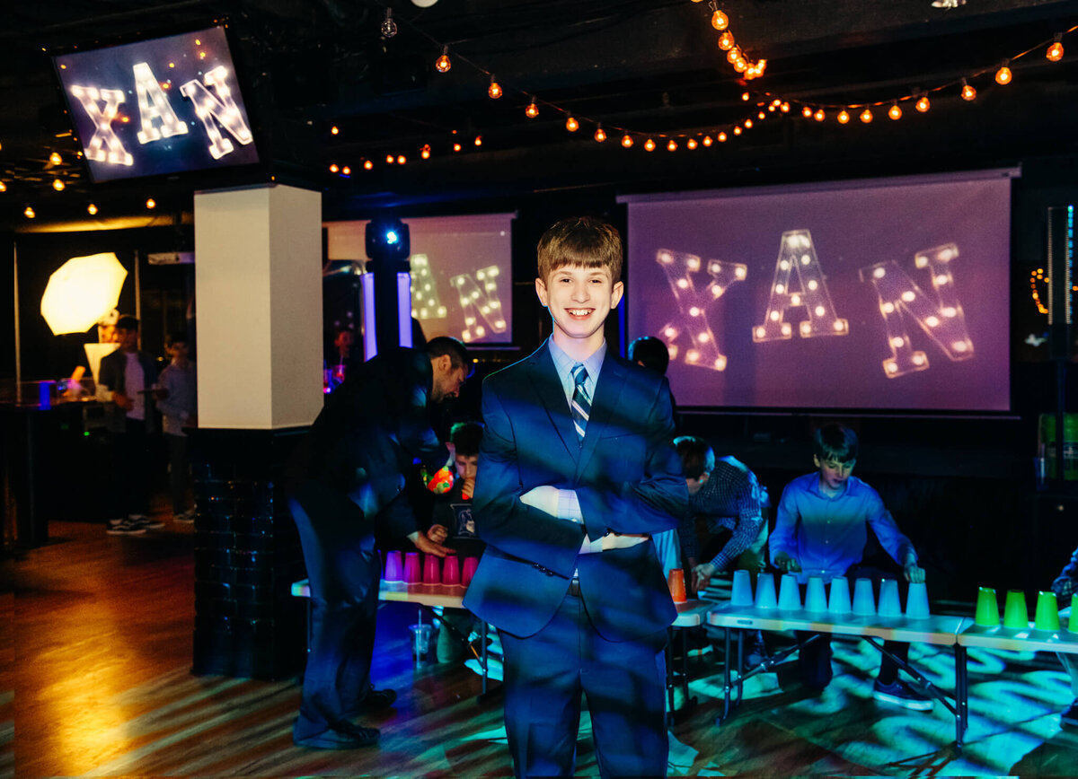 A boy stands in a blue suit on the dance floor with arms crossed for some Bellevue Bar and Bat Mitzvah Photography