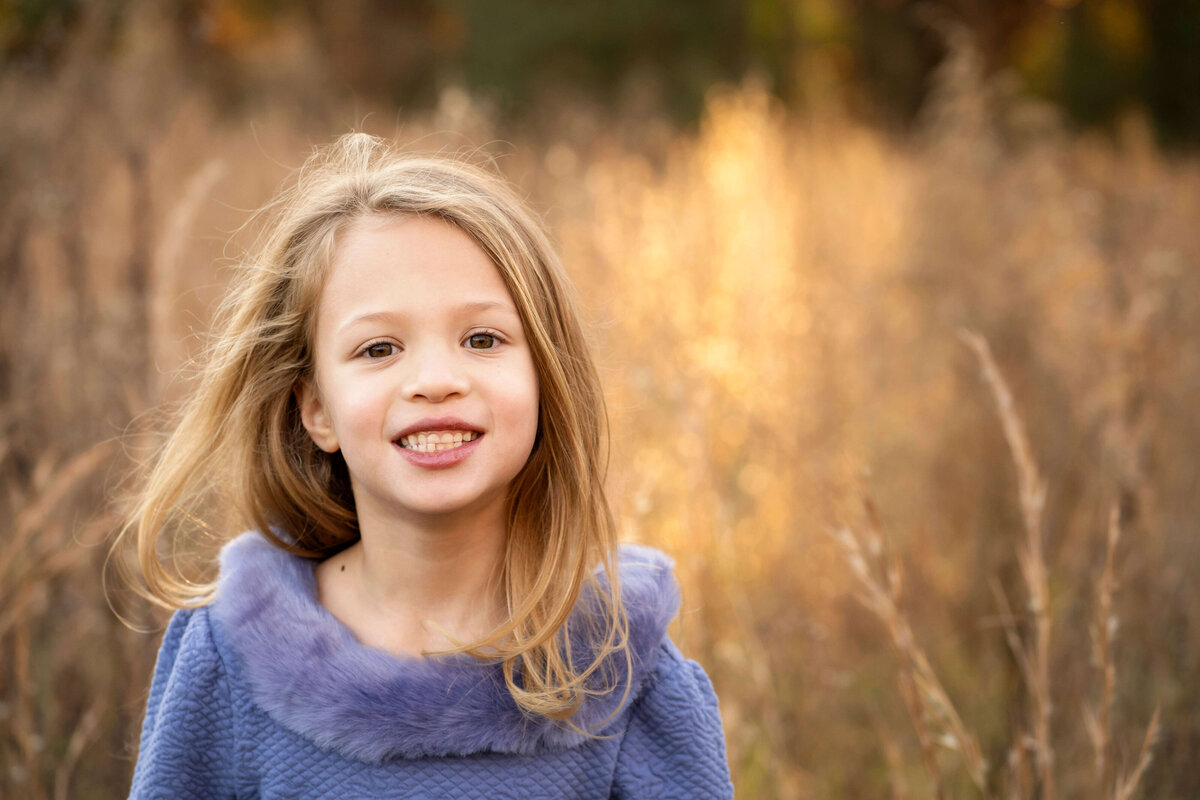 Young girl in sunset field smiling at the camera by Atalnta Family photographer