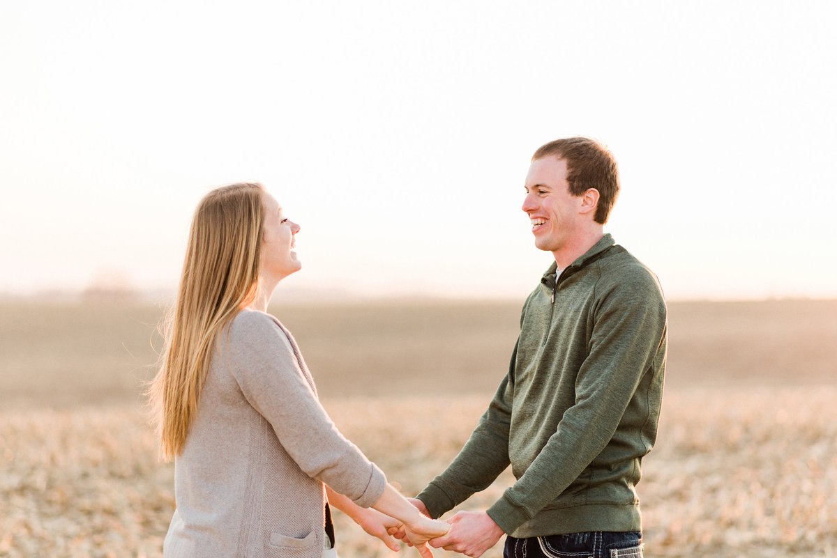 Couple holds hands at sunset engagement session in iowa