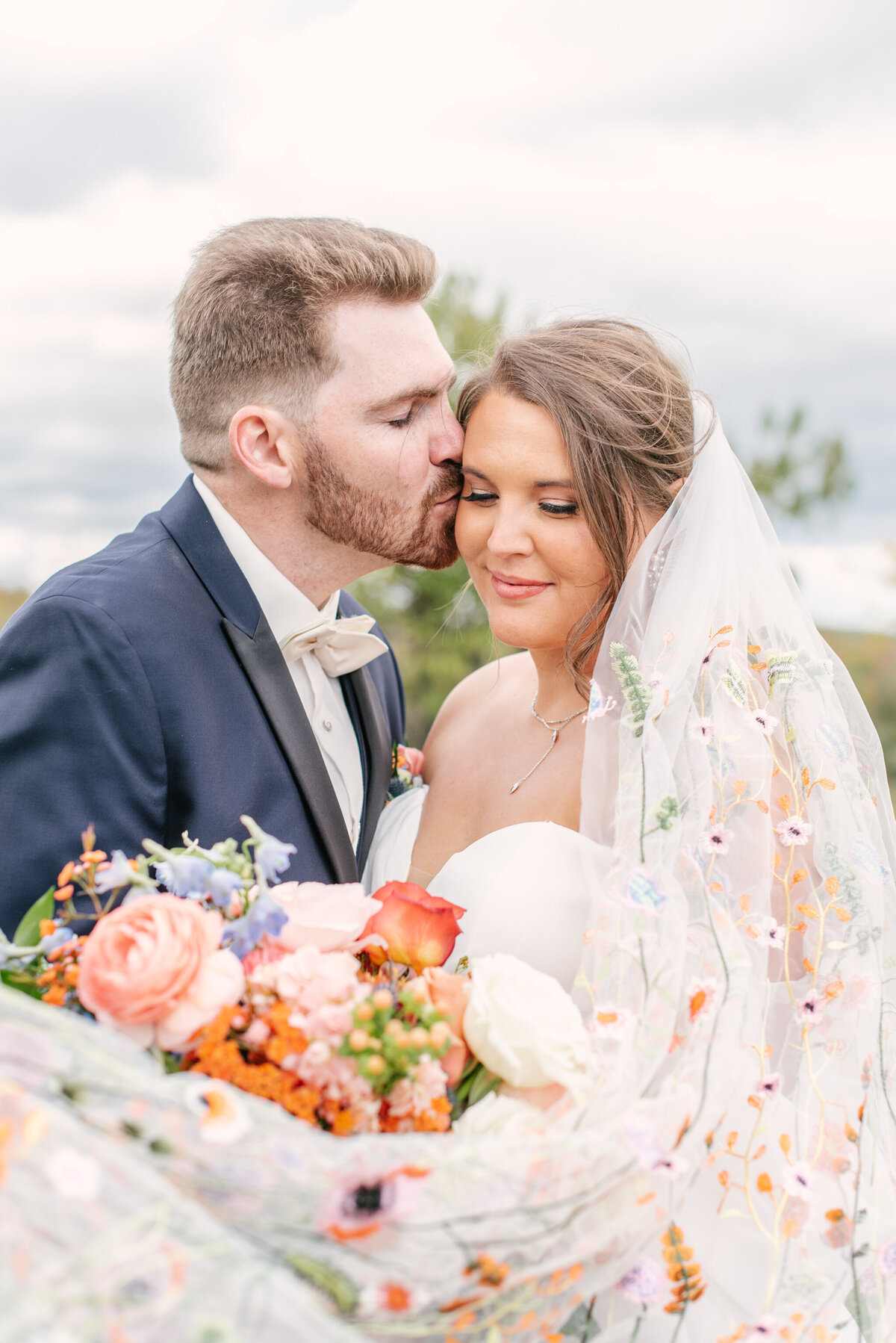 custom floral veil with orange flowers bride and groom kissing