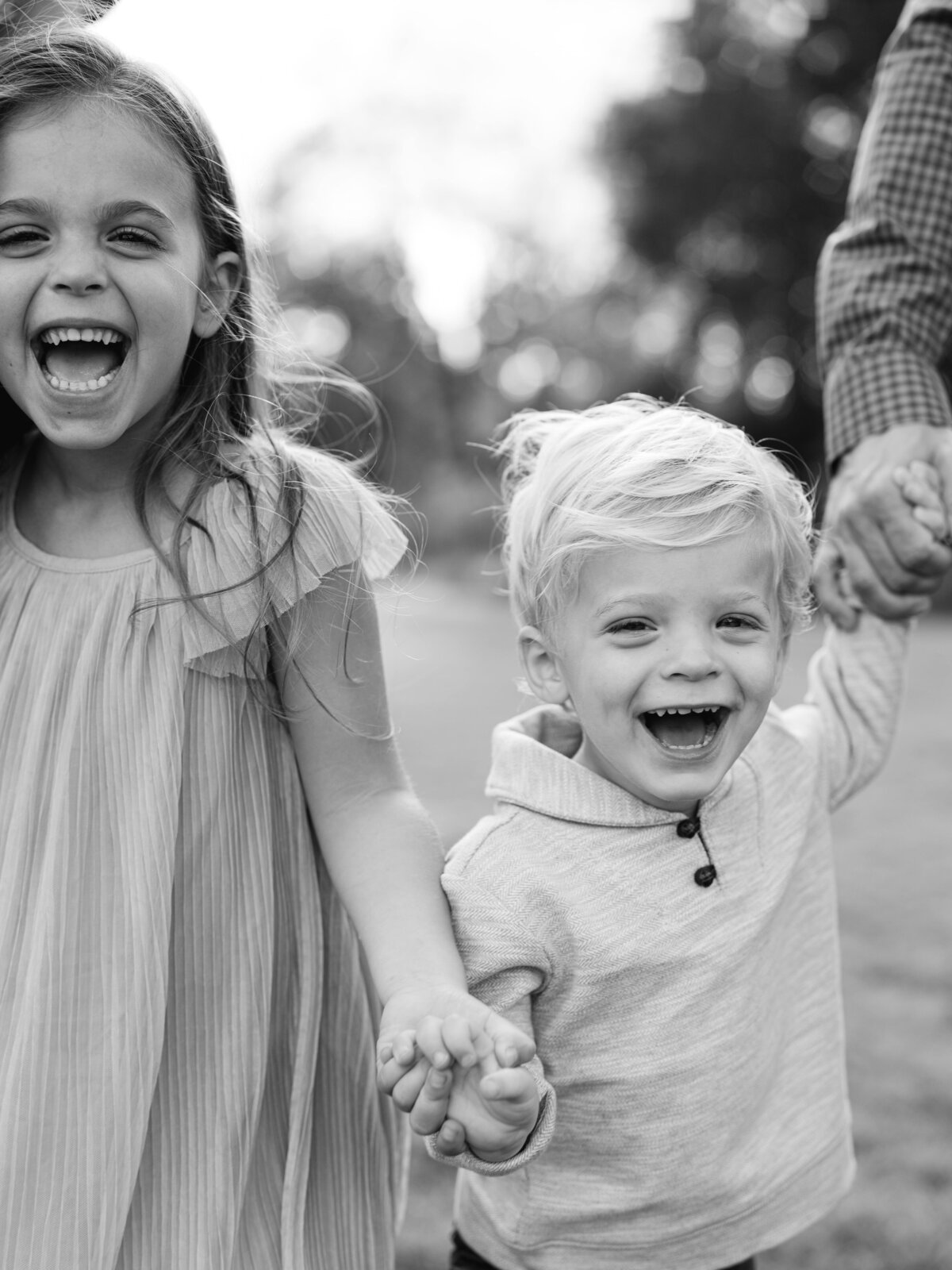 Young brother and sister holding hands and laughing