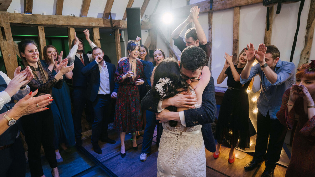 A bride and groom dancing with their friends during their wedding reception.