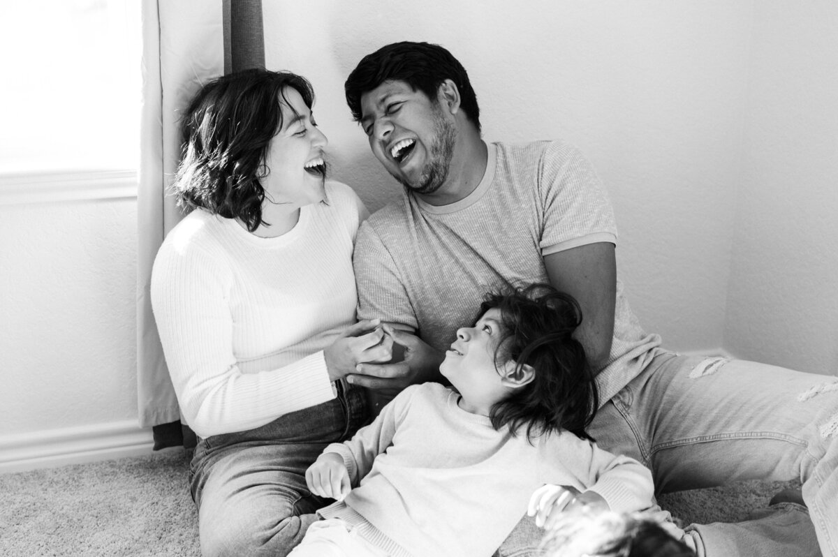 Parents laugh together during a family photoshoot.
