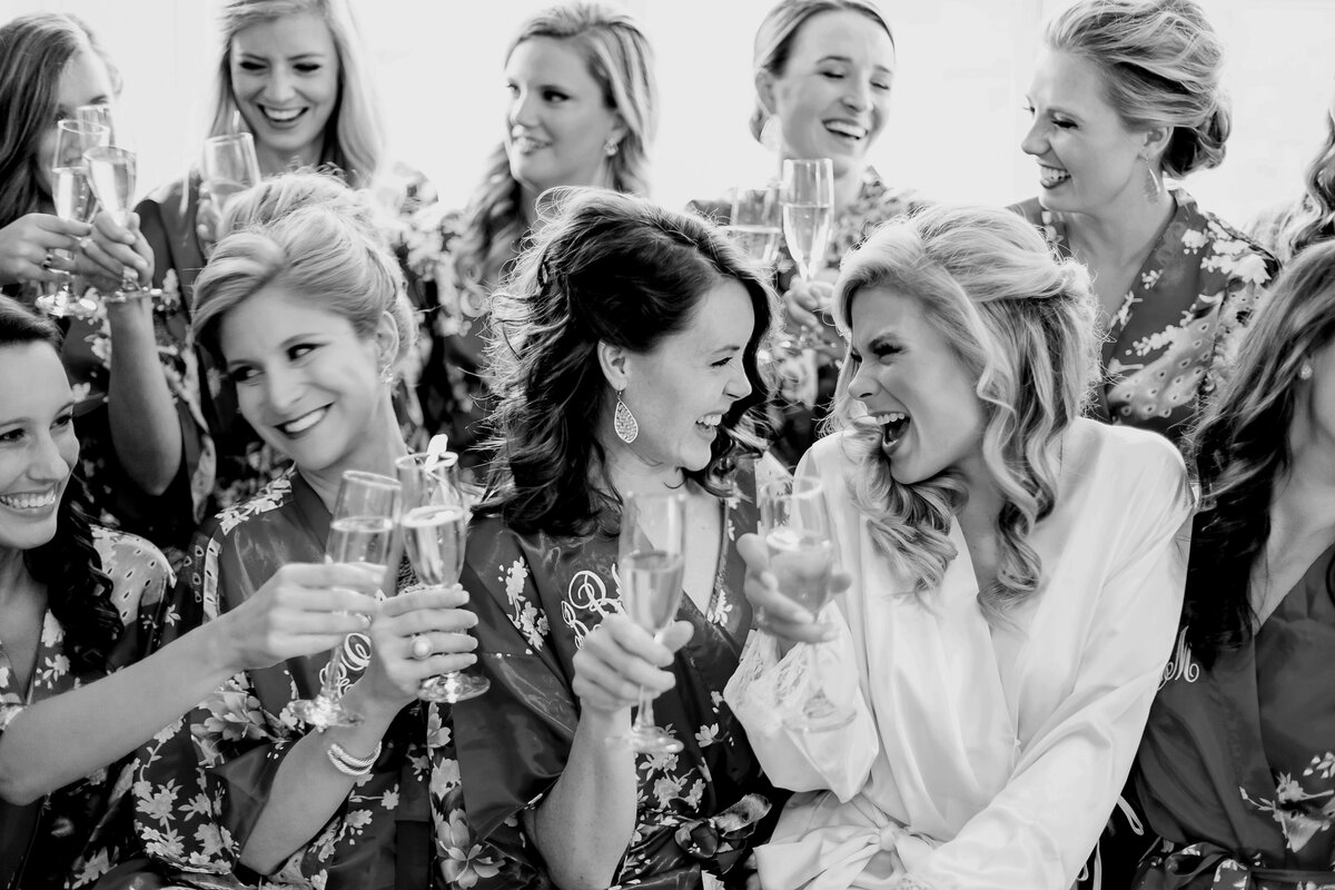 A bride holding champagne is surrounded by her bridesmaids at the Broadmoor